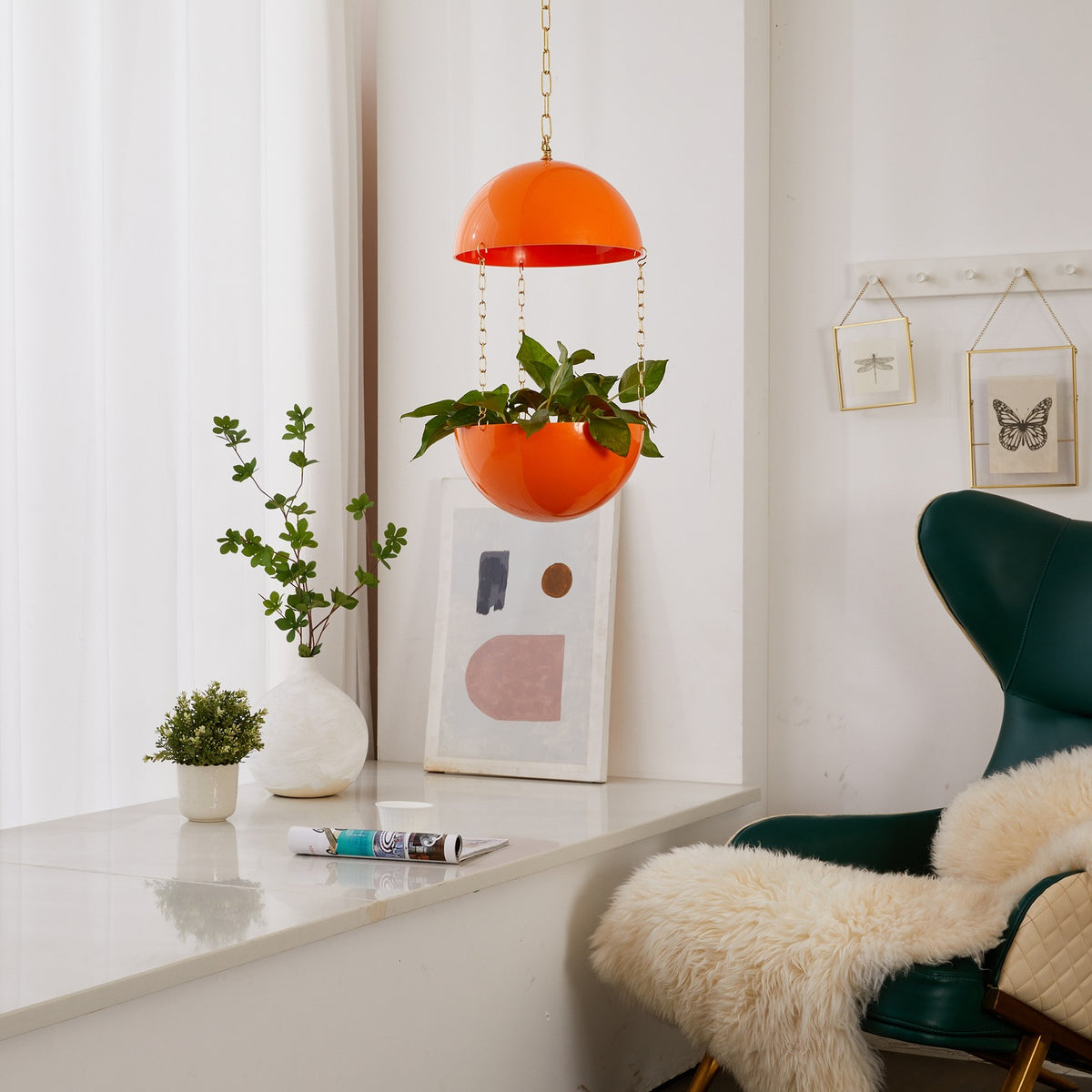 Solar Orange Potifiv Pendant Planter with a trailing plant, hanging in a mid century modern interior